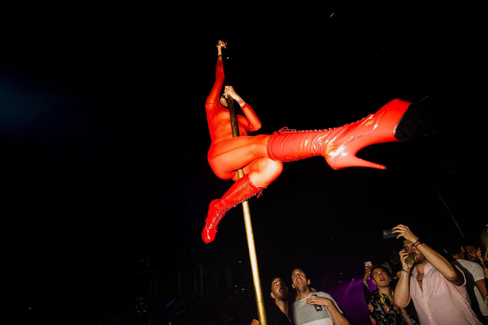 Pole performer in red latex above the crowd at Devils Playground, New York