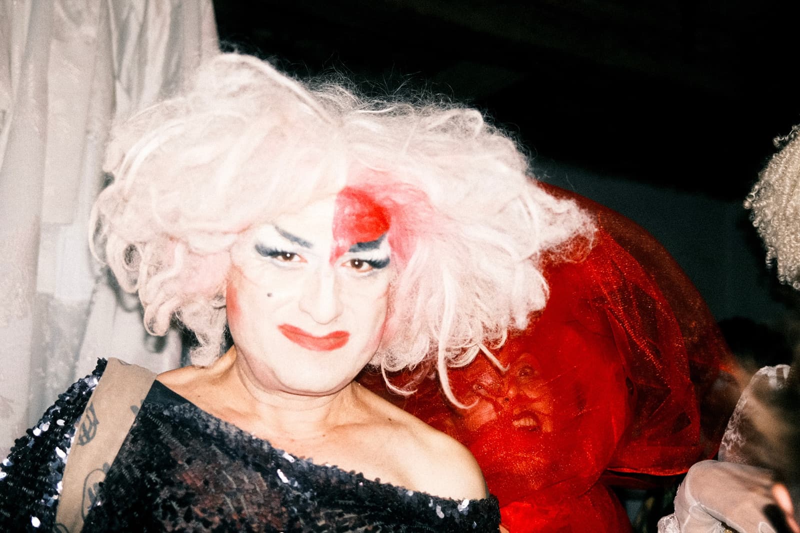 Performer in a towering white wig, up close in the flash